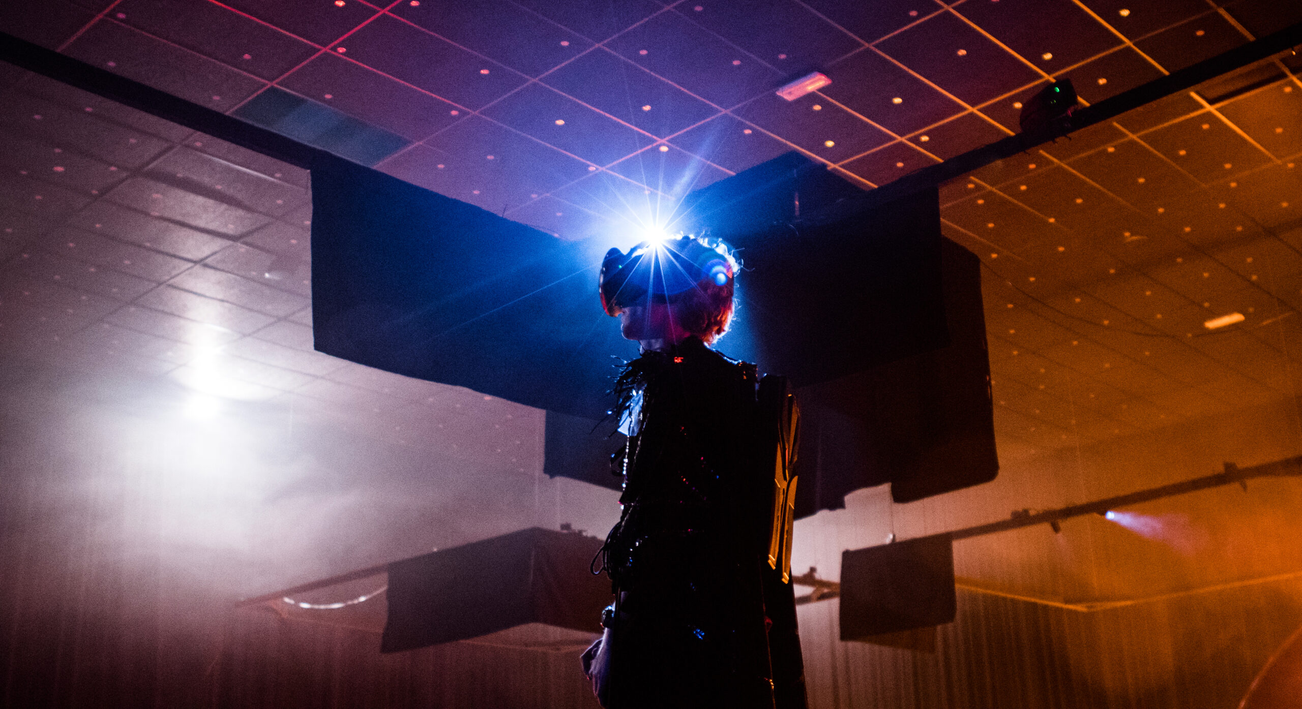 The original XR BLACK BOX homepage photograph: A person wearing a VR headset beneath blue and orange stage lighting.